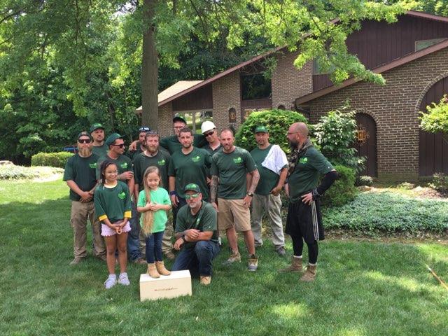 The team from Jim's All Seasons, LLC with children wearing green shirts in the front yard of a house in Cleveland, OH